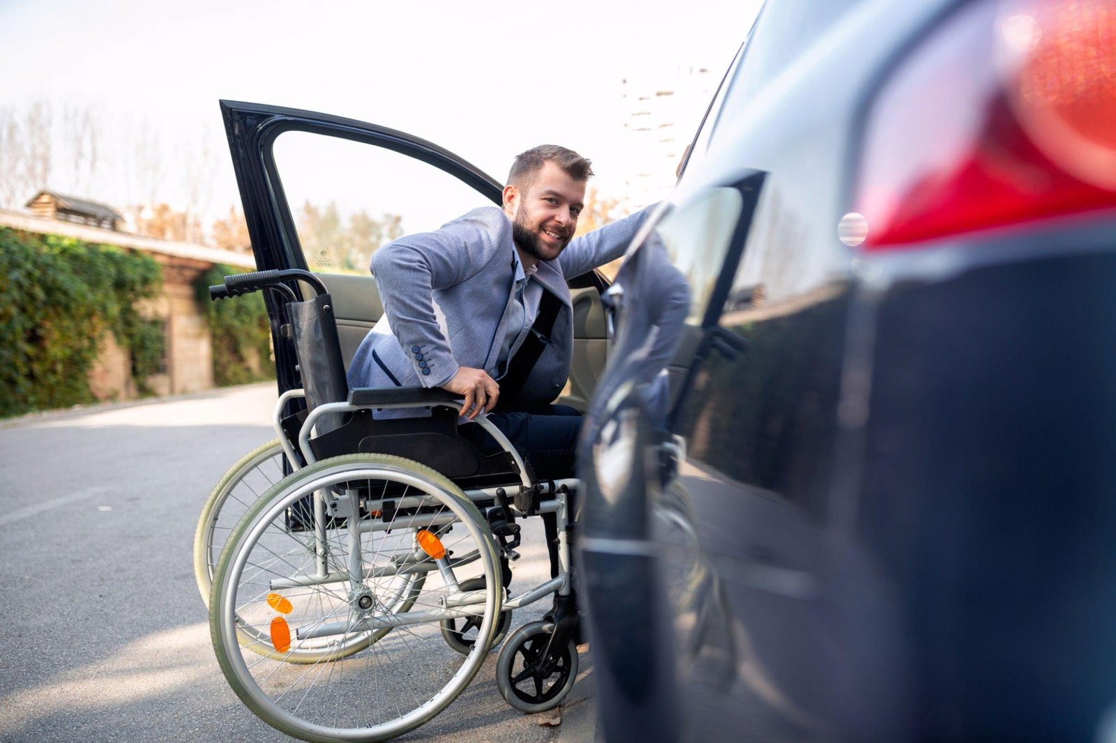 man in wheelchair getting into car